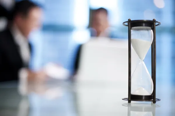 Hourglass on the meeting table — Stock Photo, Image