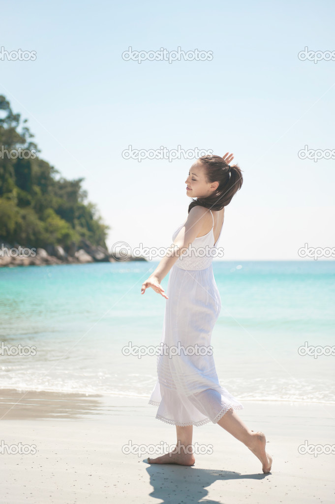 Attractive Asian female walking on the beach