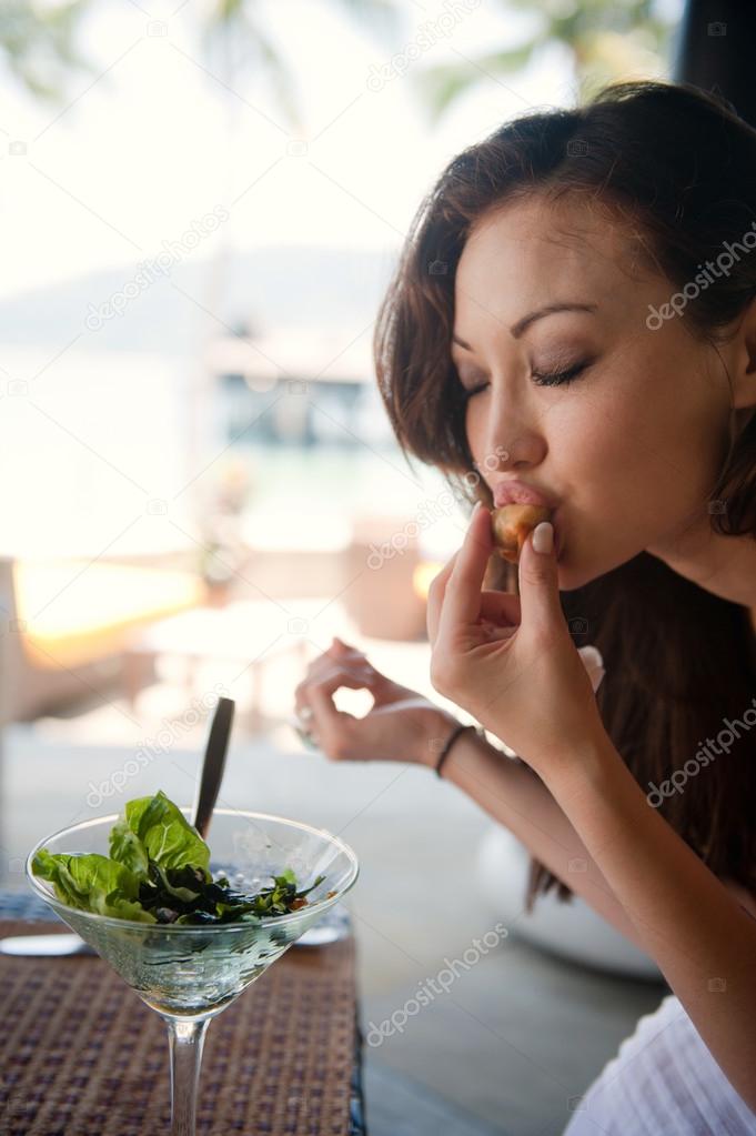 asian girl tasting a finger food at a restaurant