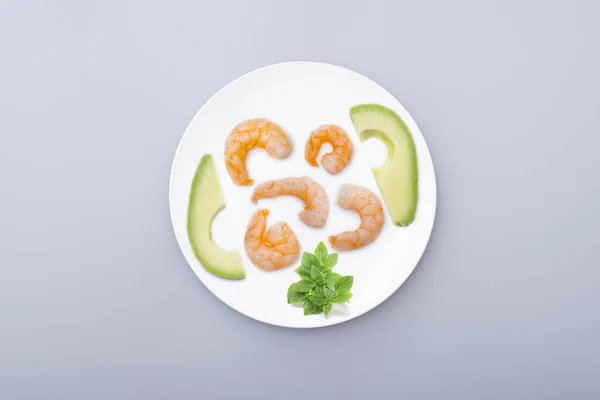 White ceramic plate with seafood, boiled shrimps, avocado. Minimal concept picture about diet, healty lifestyle. Top view.