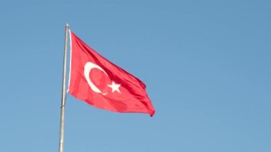 Türkiye 'nin İstanbul kentinde güneşli bir yaz sabahı mavi gökyüzünde dalgalanan büyük bir Türk bayrağı veya bayrağı