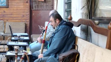 İSTANBUL - OCT 22: Türk erkekler sabah eski bir kafede nargile tüttürüyor. 22 Ekim 'de İstanbul' da Türkiye için geleneksel olan doğal su borularını içen bir grup erkek. 2021 