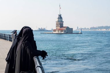 Geleneksel Müslüman kıyafetli iki kadın siyah tesettür, çarşaf giyiyor ve İstanbul, Türkiye 'de toprak setinde yürüyor