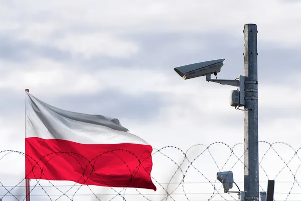 Polonya bayrağı dikenli tellerin ve güvenlik kameralarının arkasında.