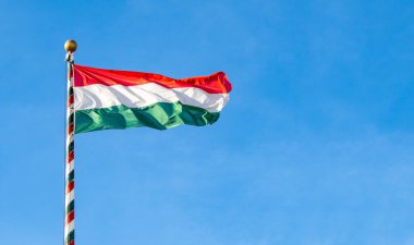 Hungarian flag or flag of Hungary waving against blue sky, space for text clipart