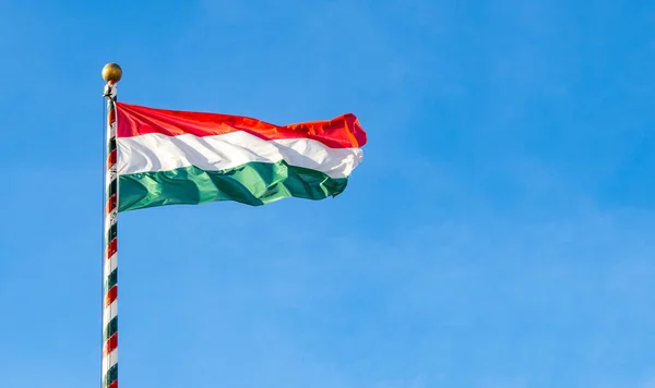 Hungarian flag or flag of Hungary waving against blue sky, space for text