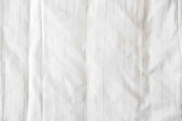 White bed linen, sheet as texture or background, crumpled blank bedclothes top view