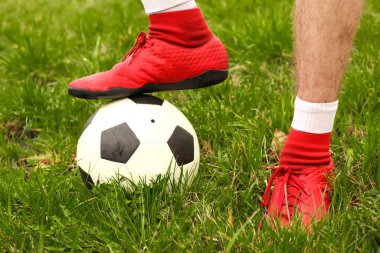Oyuncular sahada mini futbol oynarlar. Bacaklar, spor ayakkabılar ve bir top. Yeşil futbol sahası.