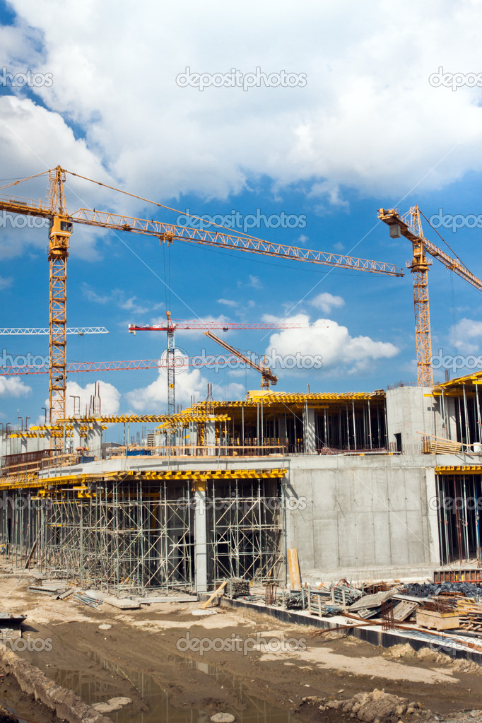 building and cranes under construction against blue sky