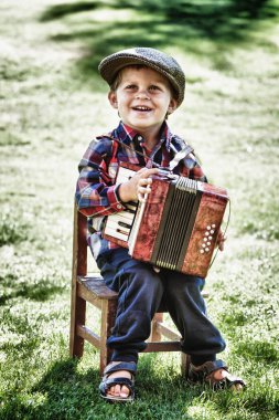 happy young boy playing accordion in summer clipart