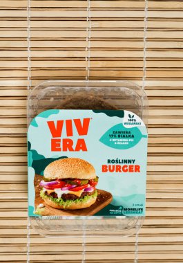 RZESZOW, PODKARPACKIE POLAND - 26 Ocak 2022: Ahşap zemin üzerinde soya fasulyesi ve buğday proteininden yapılmış Bitki Burger VIVERA ambalajı ve içindekiler