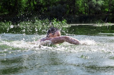 Genç adam nehirde yüzüyor..