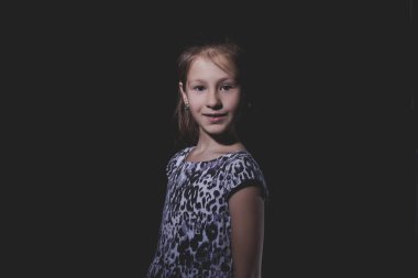 Siyah arka planda küçük tatlı bir kızın portresi. Gösterişsiz stüdyo fotoğrafı.