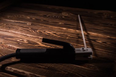 Kaynak elektrot tutacağı ve ahşap bir arka planda elektrot. Stüdyo fotoğrafı sert ışıkta.