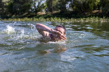 Genç adam nehirde yüzüyor..