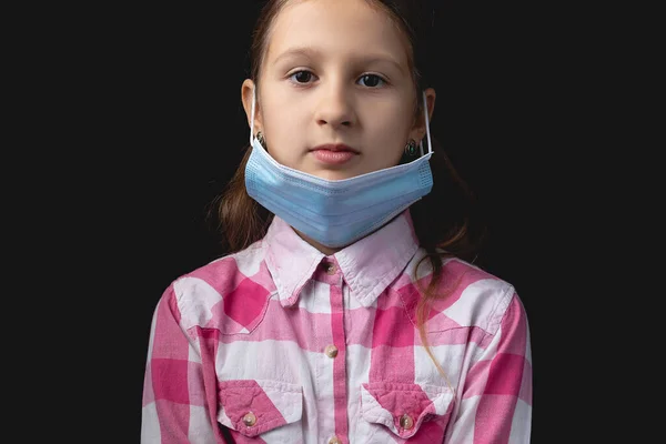 青い医療マスクの少女 医療用マスクを誤って着用するという概念 1つの光源で黒の背景に隔離されたスタジオの肖像画 — ストック写真
