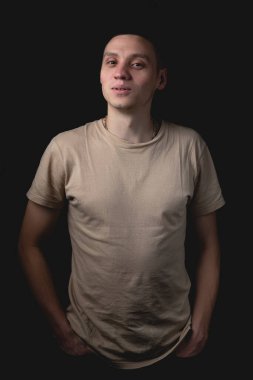 Siyah arka planda poz veren yakışıklı bir genç. Stüdyo fotoğrafı ve tek bir ışık kaynağı. Gülümseyen adam stüdyoda neşeyle poz veriyor..