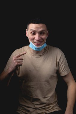 Yakışıklı bir genç adam ve siyah bir geçmişi olan tıbbi bir maske. Adam tıbbi maske takmanın ne kadar yanlış olduğunu gösteriyor..
