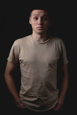 Siyah arka planda poz veren yakışıklı bir genç. Stüdyo fotoğrafı ve tek bir ışık kaynağı. Gülümseyen adam neşeli bir şekilde stüdyoda poz veriyor. Adam öfkeyle önüne bakıyor..