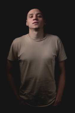 Siyah arka planda poz veren yakışıklı bir genç. Stüdyo fotoğrafı ve tek bir ışık kaynağı. Adam önüne bakıyor, başını arkaya atıyor..