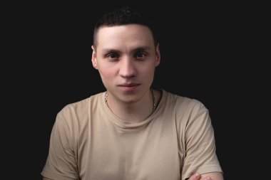 Siyah arka planda poz veren yakışıklı bir genç. Stüdyo fotoğrafı ve tek bir ışık kaynağı. Gülümseyen adam neşeli bir şekilde stüdyoda poz veriyor. Pozitif adam onun önünde utangaç görünüyor..