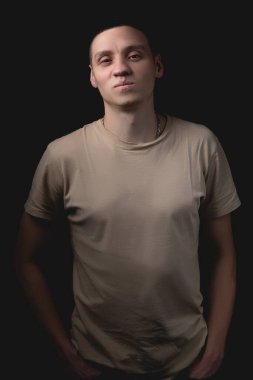 Siyah arka planda poz veren yakışıklı bir genç. Stüdyo fotoğrafı ve tek bir ışık kaynağı. Gülümseyen adam stüdyoda neşeyle poz veriyor..