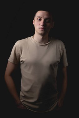 Siyah arka planda poz veren yakışıklı bir genç. Stüdyo fotoğrafı ve tek bir ışık kaynağı. Gülümseyen adam neşeli bir şekilde stüdyoda poz veriyor. Ciddi adam onun önüne iyi niyetle bakar..