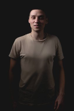 Siyah arka planda poz veren yakışıklı bir genç. Stüdyo fotoğrafı ve tek bir ışık kaynağı. Gülümseyen adam stüdyoda neşeyle poz veriyor..
