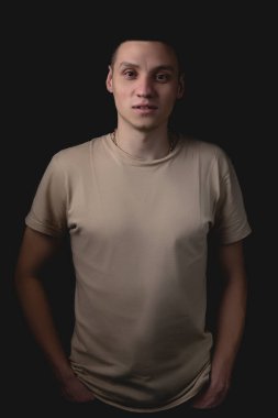Siyah arka planda poz veren yakışıklı bir genç. Stüdyo fotoğrafı ve tek bir ışık kaynağı. Gülümseyen adam neşeli bir şekilde stüdyoda poz veriyor. Adam onun önünde merakla bakıyor..
