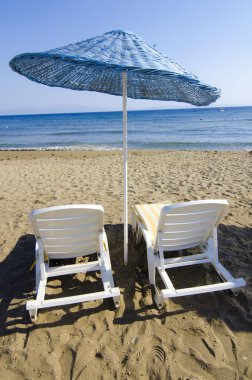 kumsalda güneşlik ve şemsiyeler