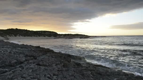 Oceaan golven lappen het strand bij zonsondergang — Stockvideo