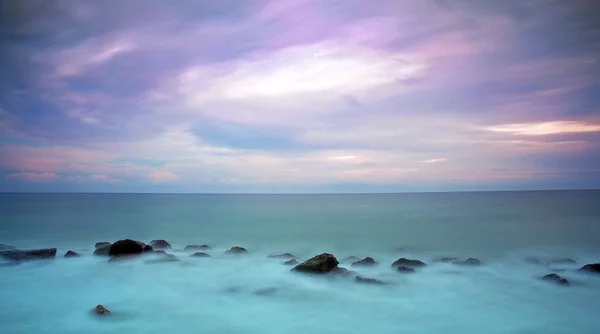 Восход солнца с камнями в океане — стоковое фото
