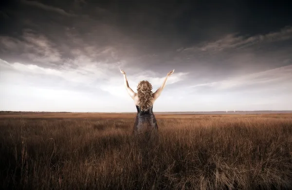 Woman lifting her hands up in a field — Stock Photo, Image