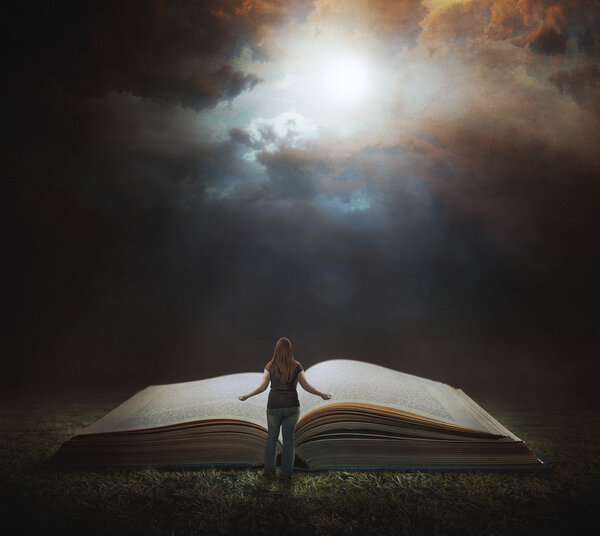Woman reading large book at night