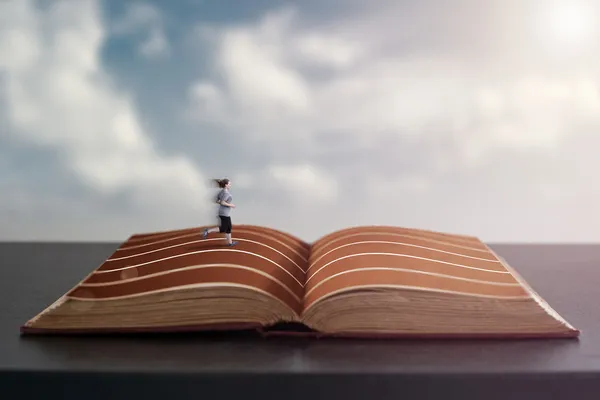 Uma mulher correndo em uma pista nas páginas de um livro . — Fotografia de Stock