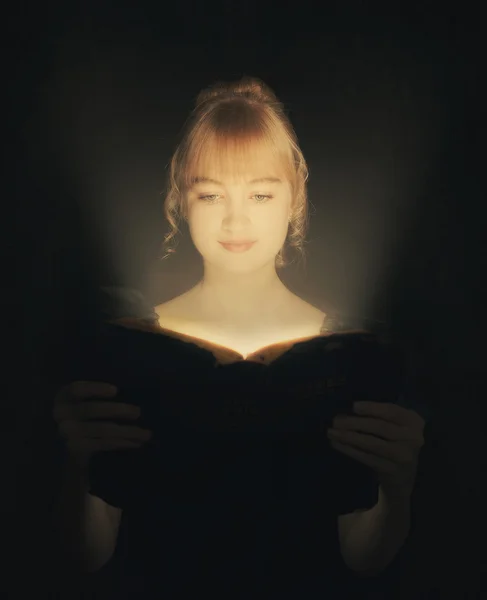 Woman reading a glowing Bible. — Stock Photo, Image