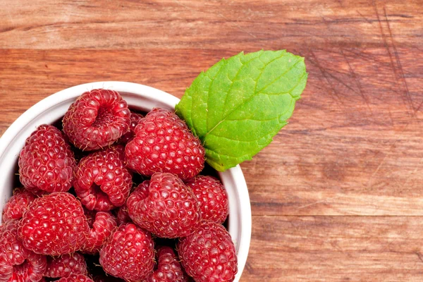 Bowl of raspberries on an old wooden table — Stock Photo, Image