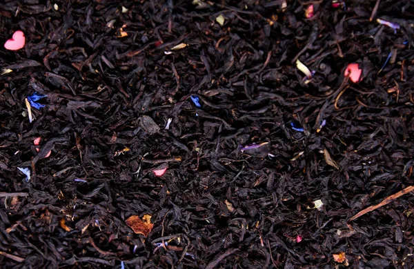 black leaf tea with flower petals close-up