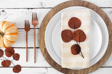 Sonbahar hasadı ya da tabak, çatal, peçete ve sonbahar dekorlu şükran günü sofrası. Beyaz ahşap arka planda üst görünüm.