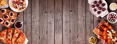 Kış tatili için aperatifler. Koyu ahşap bir arka planda çift kenarlı manzaranın üstünde. Diyet ekmek, şiş, yaban mersinli crostini ve çeşitli parti yemekleri. Boşluğu kopyala.