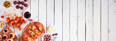 Kış tatili için aperatifler. Beyaz ahşap bir arka planda üst köşenin kenarı. Düz ekmek, şiş, yaban mersinli crostini ve çeşitli parti yemekleri. Boşluğu kopyala.