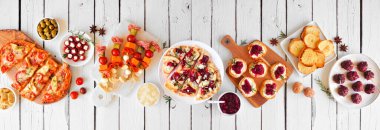 Kış tatili için aperatifler. Beyaz ahşap bir arka planda yukarıdaki masa manzarası sahnesi. Ekmek, şiş, yaban mersinli kek ve çeşitli parti yemekleri..