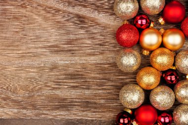 Kırmızı ve altın madalyalardan oluşan bir Noel kenarı. Kırsal ahşap arka planda tepeden aşağı bir manzara. Boşluğu kopyala.