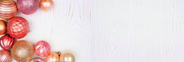 Pembe ve altın takılarla dolu bir Noel köşesi. Beyaz ahşap arka planda manzaranın üstünde. Boşluğu kopyala.