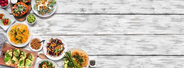 Sağlıklı bitki tabanlı düşük karbonhidratlı yemek köşesi sınırı. Beyaz ahşap bir arka plan üzerinde üst görünüm. Karnabahar ekmeği ve biftek, sebzeli erişte, lahana salatası, avokado, tatlı patates. Boşluğu kopyala.