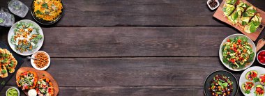 Sağlıklı bitkiler, düşük karbonhidrat diyeti, çift sınır. Koyu ahşap bir arka planda tepeden aşağı manzara. Sebzeli erişte, karnabahar ekmeği ve biftek, lahana salatası, doldurulmuş avokado ve tatlı patates..