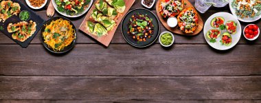 Sağlıklı bitki temelli, düşük karbonhidratlı diyet üst sınır. Koyu renk ahşap afiş arkaplanda yukarıdan görünüyor. Sebzeli erişte, karnabahar ekmeği ve biftek, lahana salatası, doldurulmuş avokado ve tatlı patates..