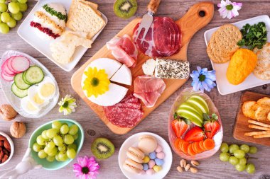 Bahar ya da Paskalya temalı şarküteri masası sahnesi ahşap arka planda. Peynir, et, meyve ve sebze mezeleri koleksiyonu. Genel Görünüm.