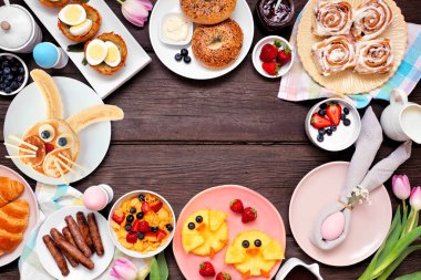 Eğlenceli Paskalya kahvaltısı ya da kahvaltı aralığı. Koyu bir ahşap arka planda, manzaranın üstünde. Tavşan gözlemesi, yumurta yuvası, civciv meyvesi ve bahar yiyecekleri koleksiyonu. Boşluğu kopyala.