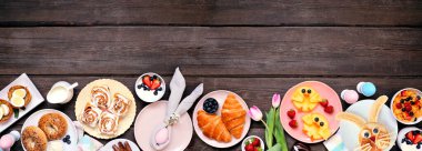 Eğlenceli Paskalya kahvaltısı ya da brunch alt sınırı. Koyu ahşap arka planda üst manzara. Tavşan gözlemesi, yumurta yuvası, civciv meyvesi ve çeşitli bahar yiyecekleri. Boşluğu kopyala.